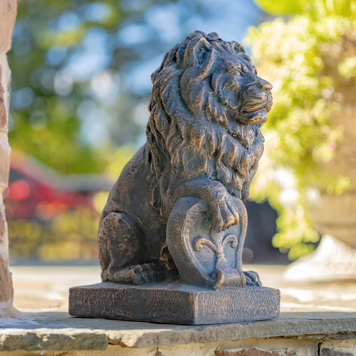 Close view of a seated lion statue with a detailed mane and paw resting on a shield.