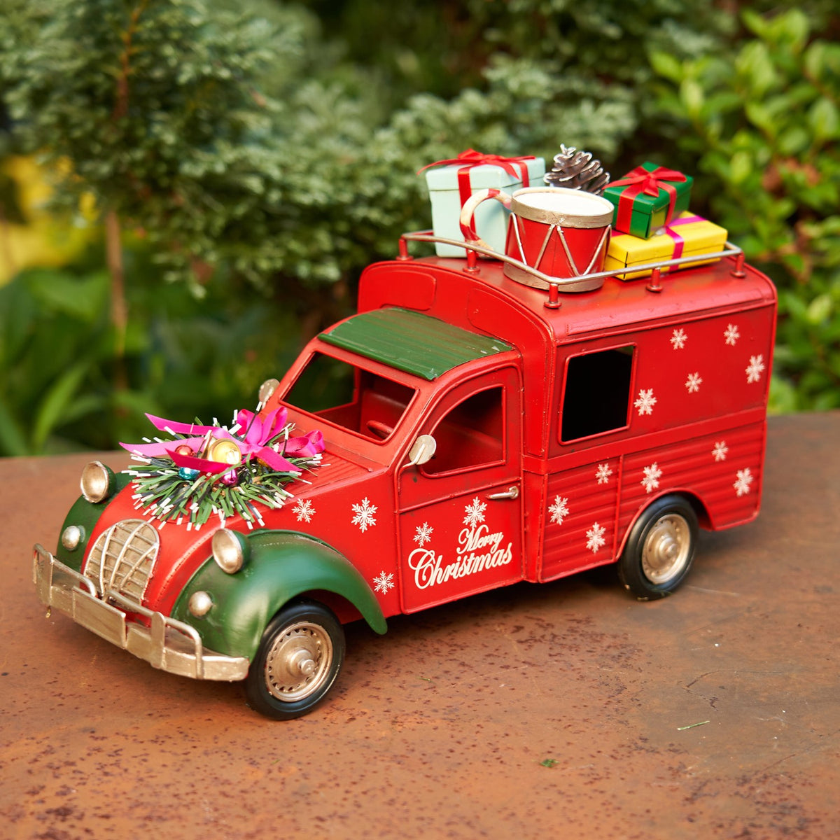 Red holiday truck with a green hood, snowy details and colorful presents displayed on top.