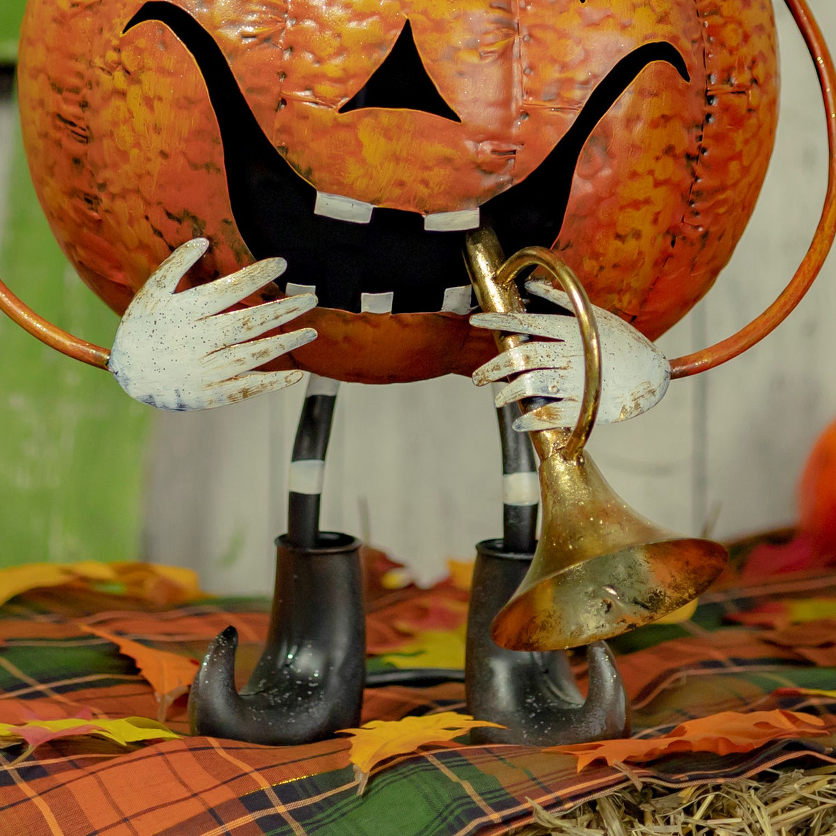 Close-up of the figurine's pale hands holding a gold trumpet above black boots