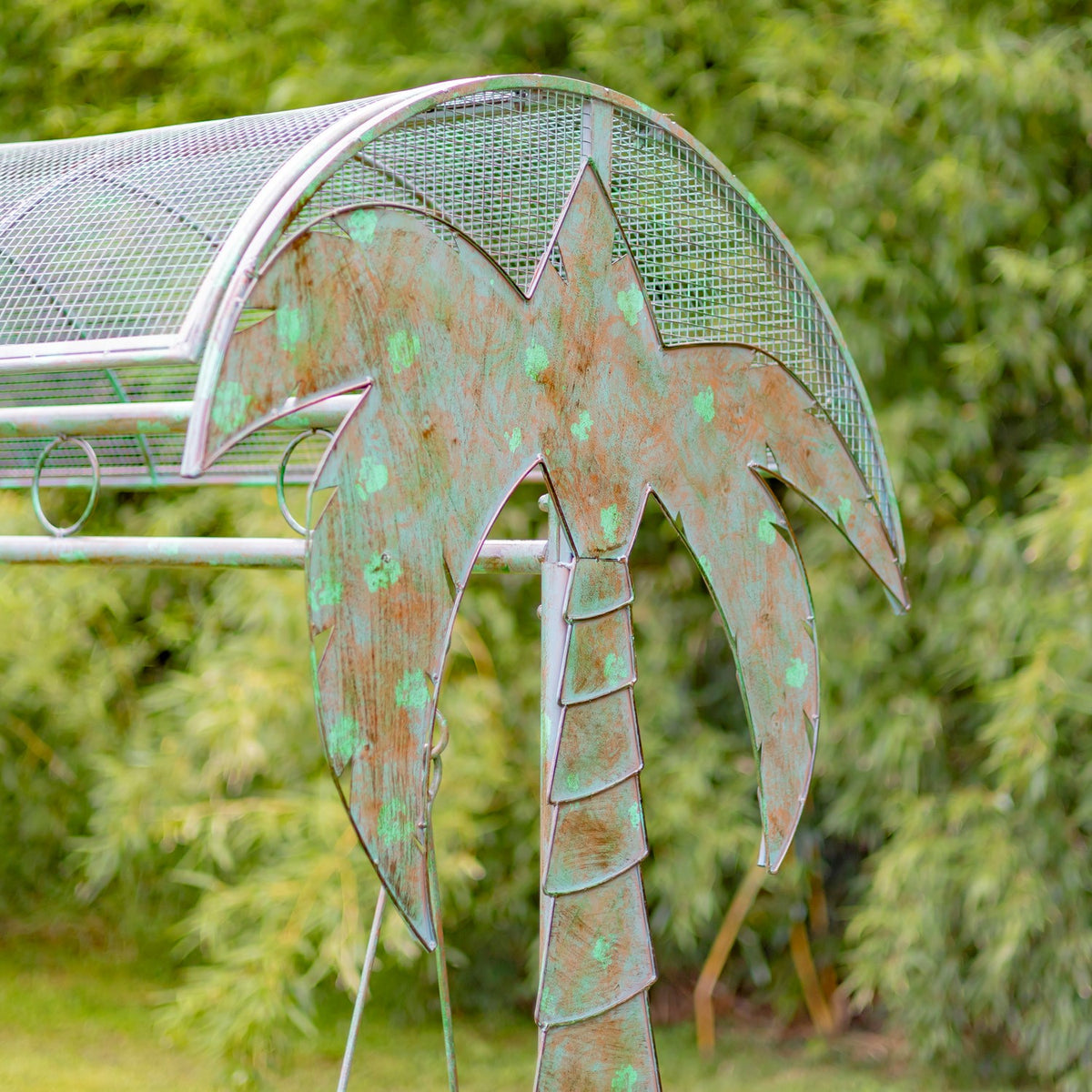 Close-up of the palm-tree decoration and mesh canopy on the green swing bench