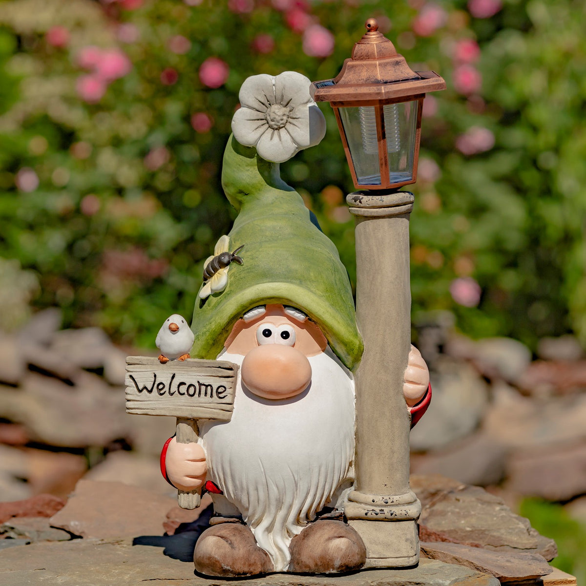 Garden gnome holding a welcome sign beside a solar lantern
