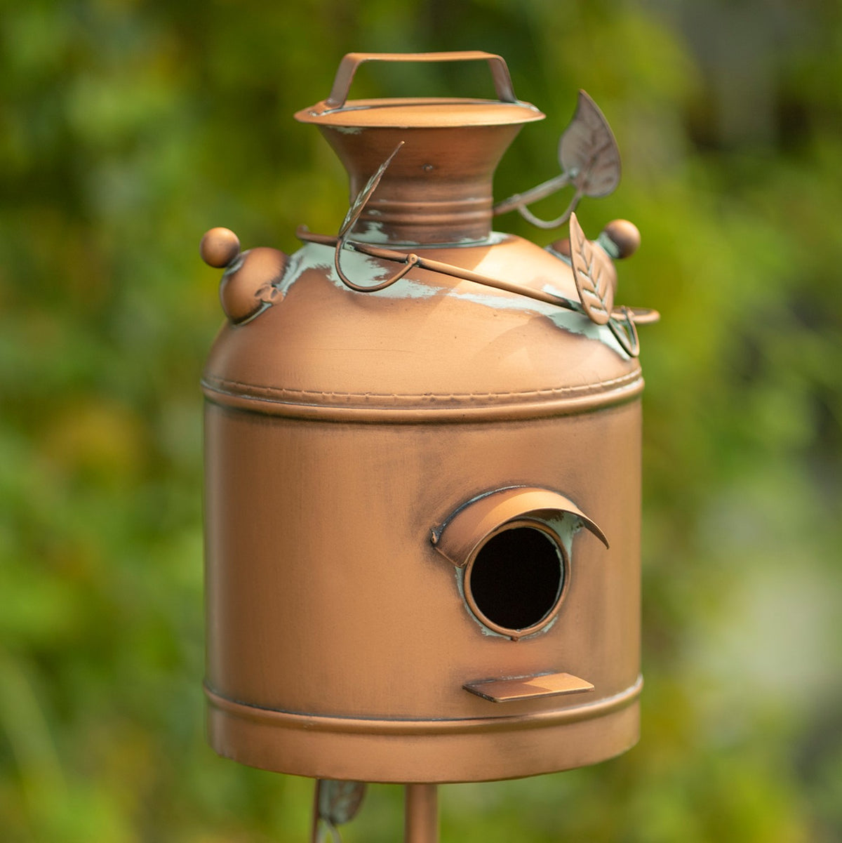 Close view of the birdhouse’s flared cap, leaf ornaments and round entrance hole.