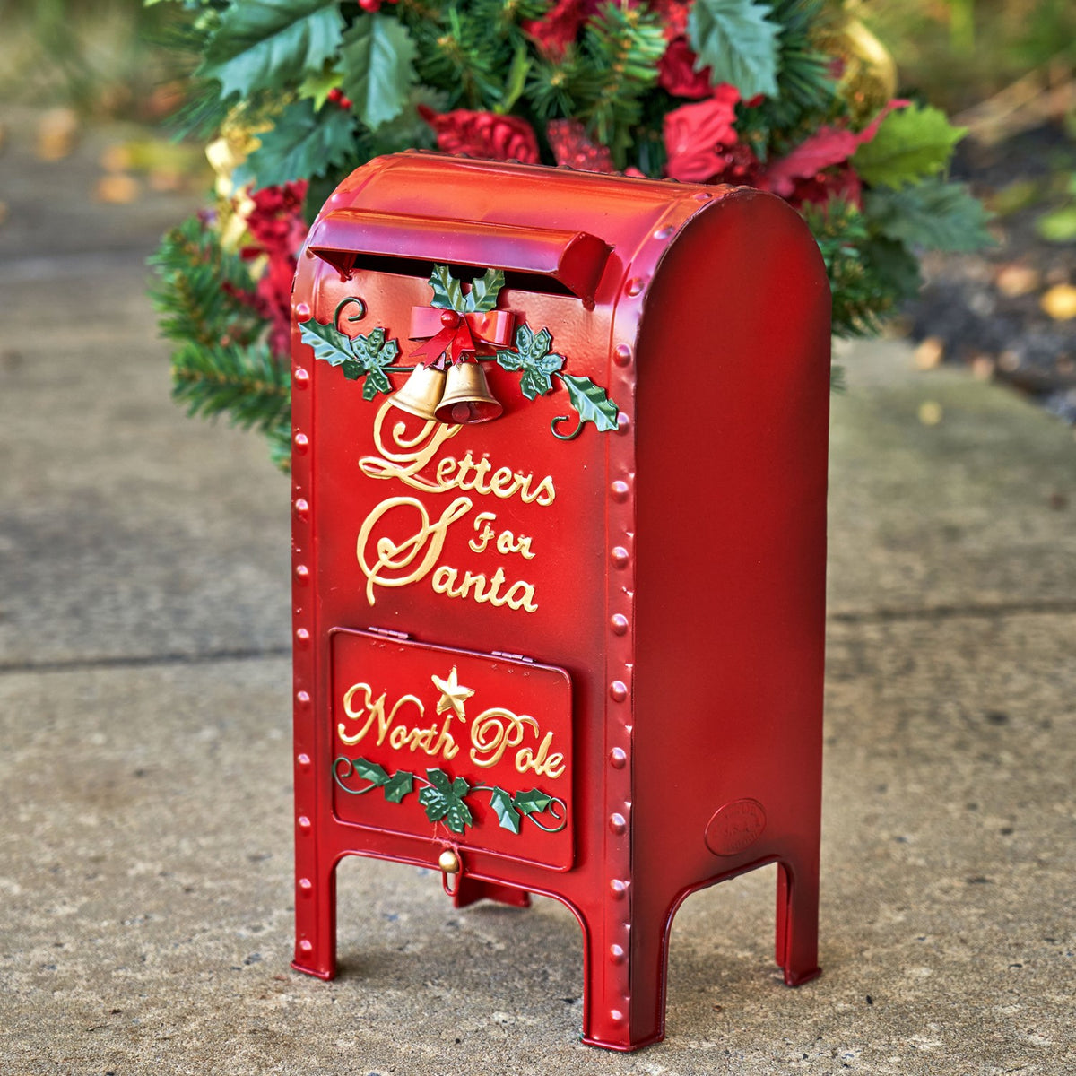 Red Christmas mailbox viewed from the side, showing its rounded body and open space beneath.