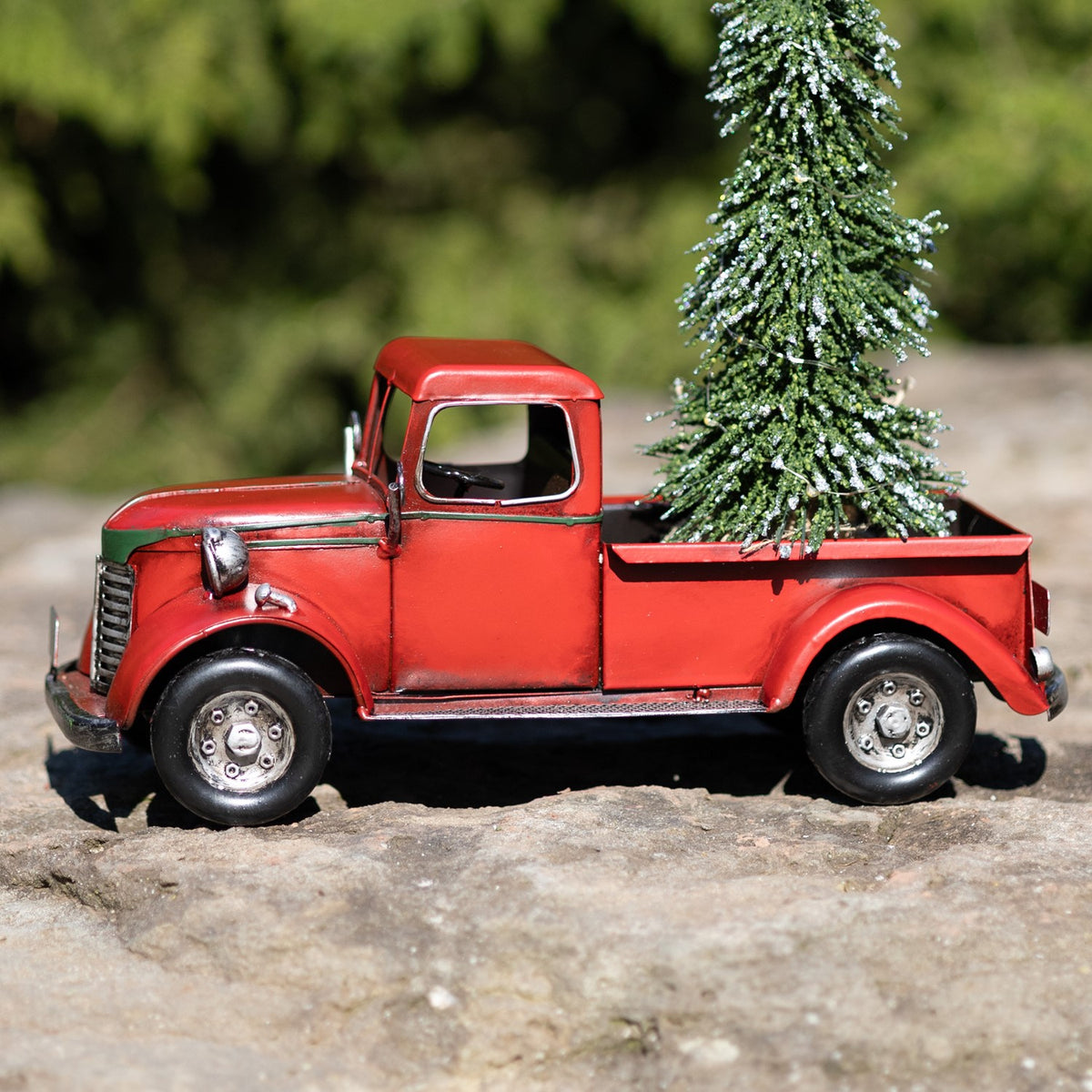 Side profile of the red pickup with a tall decorated Christmas tree rising from its open bed.