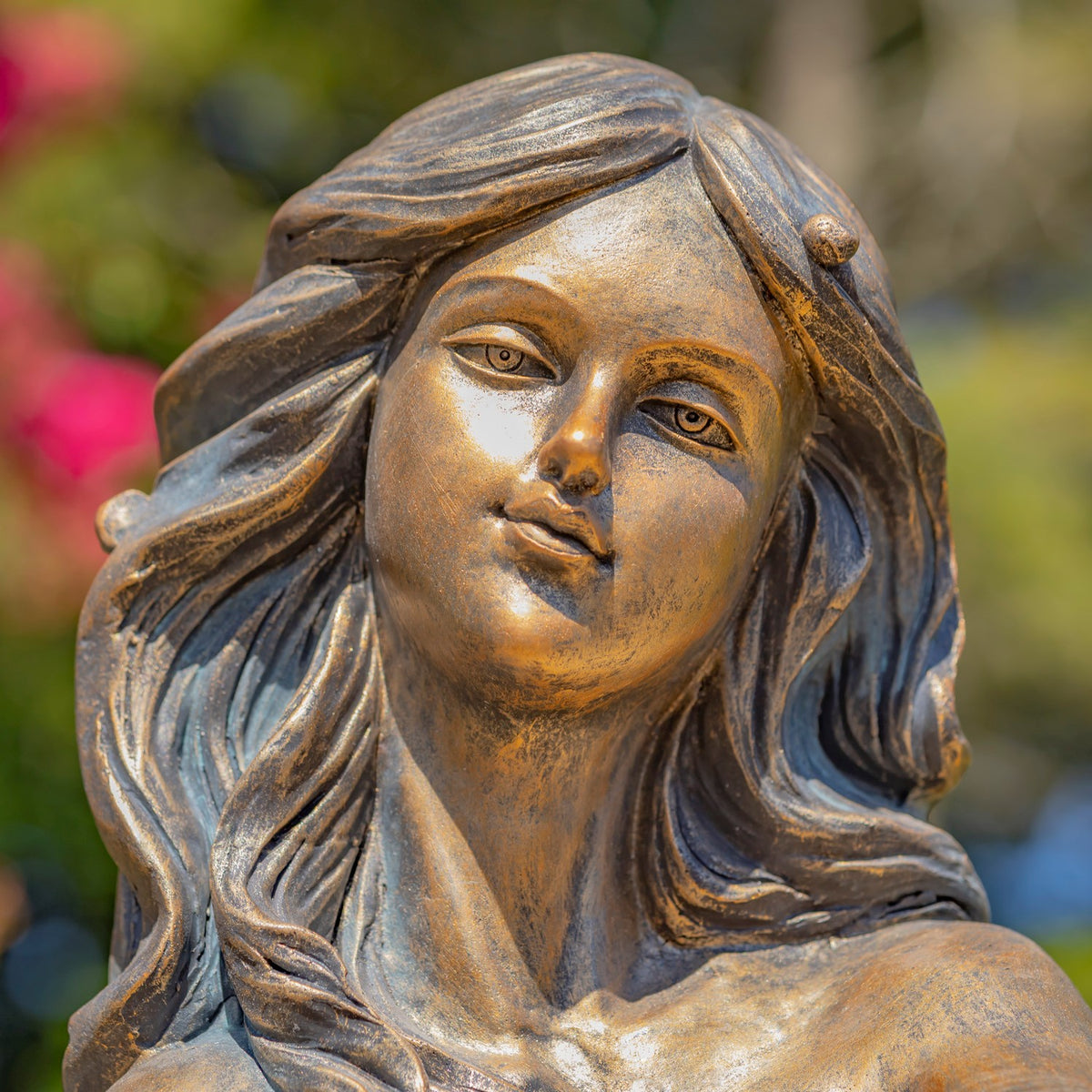 Close view of the mermaid’s face and sculpted wavy hair in a bronze-toned finish.