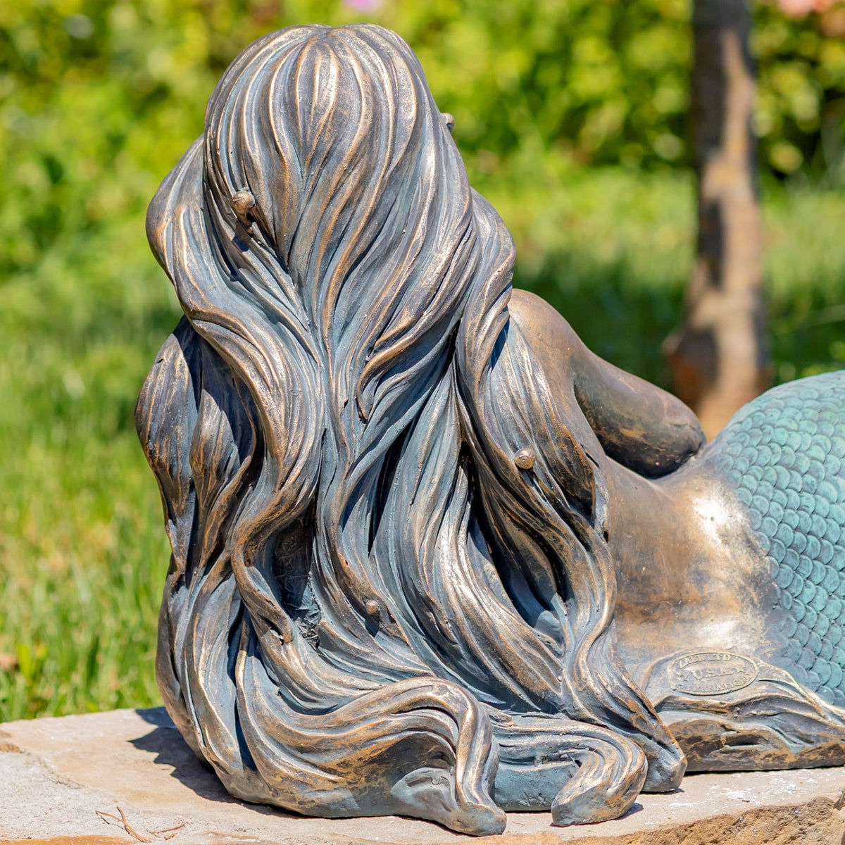 Rear view highlighting the mermaid's long, deeply sculpted hair and part of her tail.