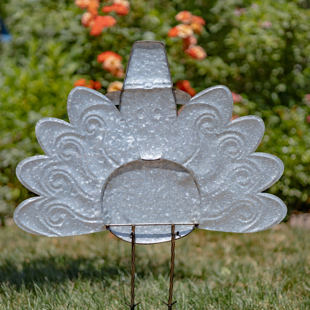 Rear of the turkey stake, showing its plain metal body, raised tail feathers and two supporting legs.