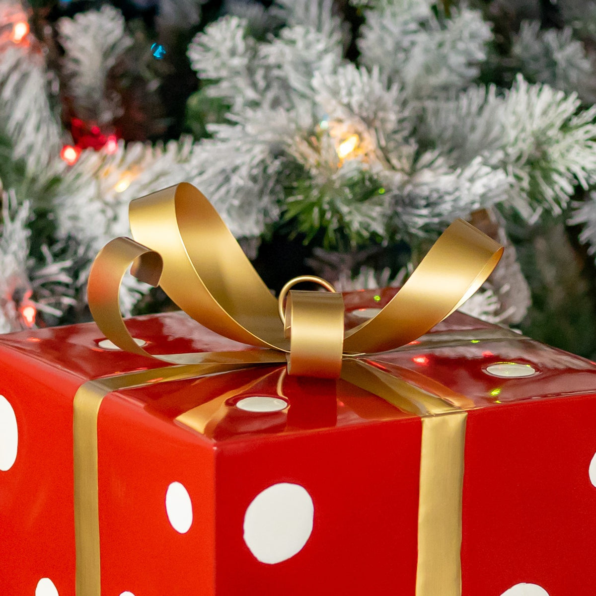Close-up of the gold ribbon bow and bands on the red, white-dotted gift box.