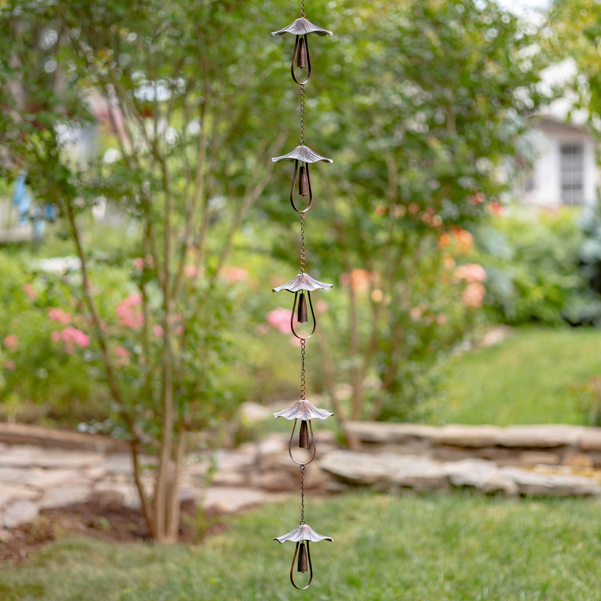 Full-length view of an antique bronze rain chain hanging in a garden