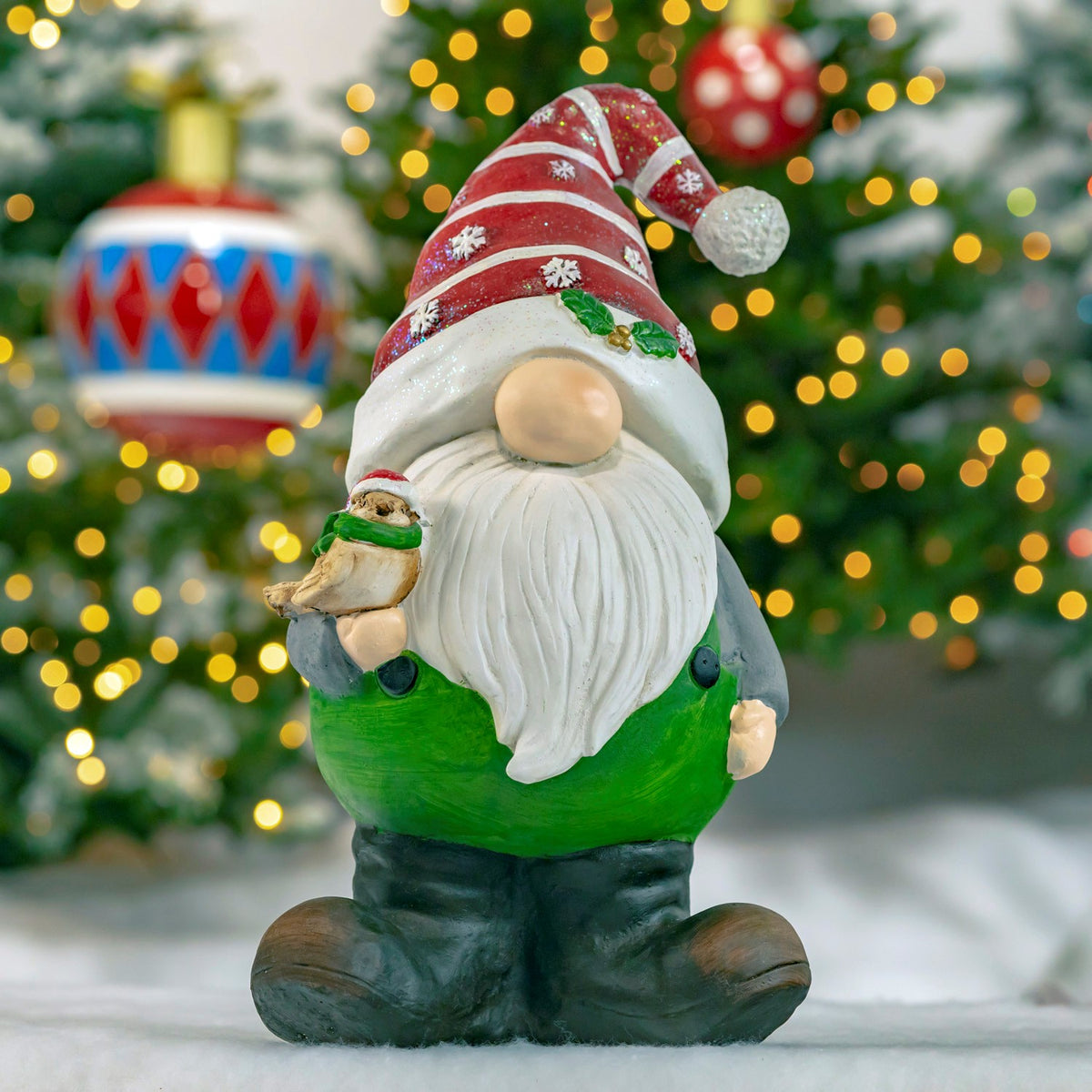 Green-clad gnome with a red striped hat holding a small bird