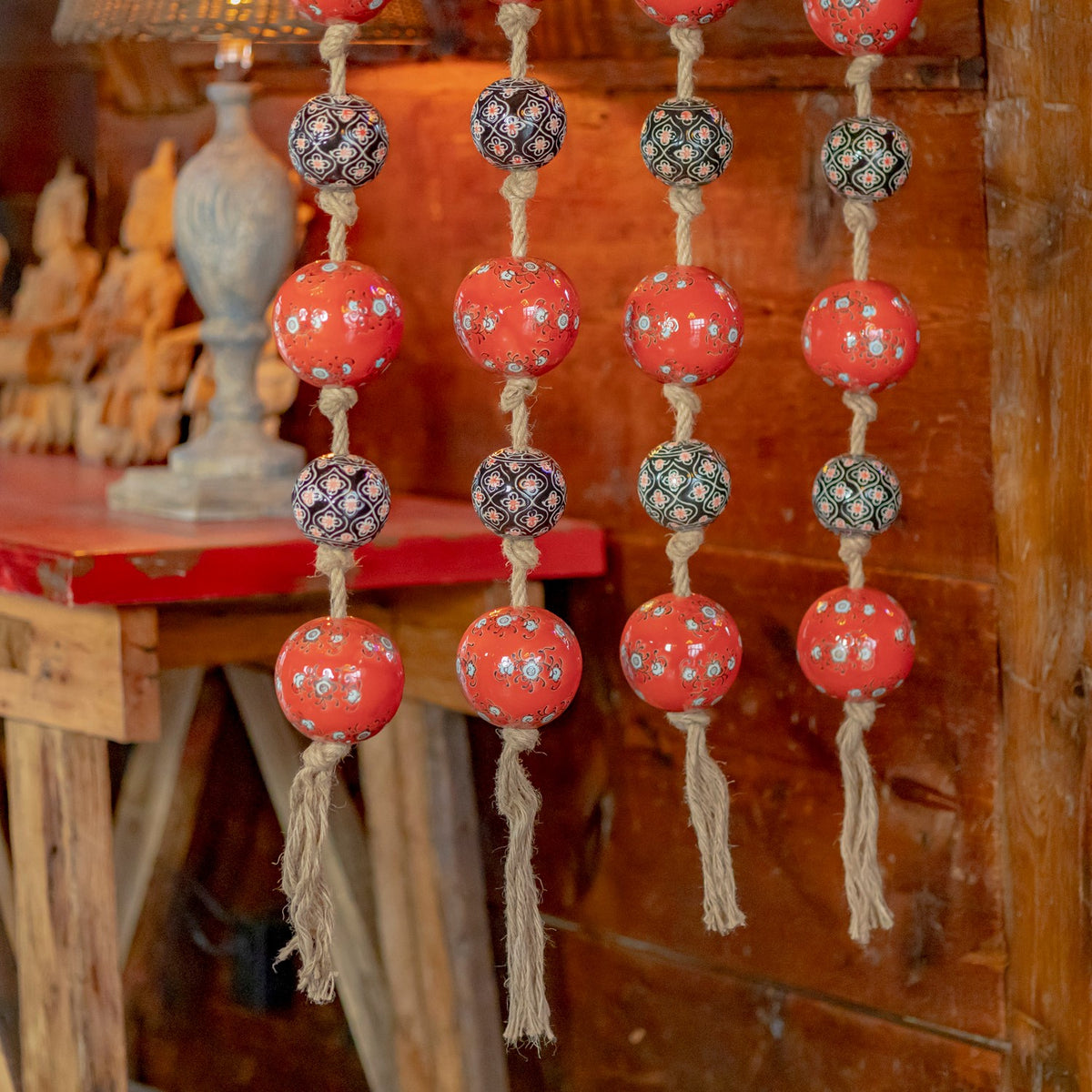 Lower sections of four rope strands show red and patterned balls with loose hanging ends.