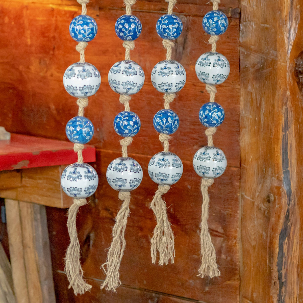 Close view of the garland strands ending in loose, frayed rope tassels beneath blue and white balls.