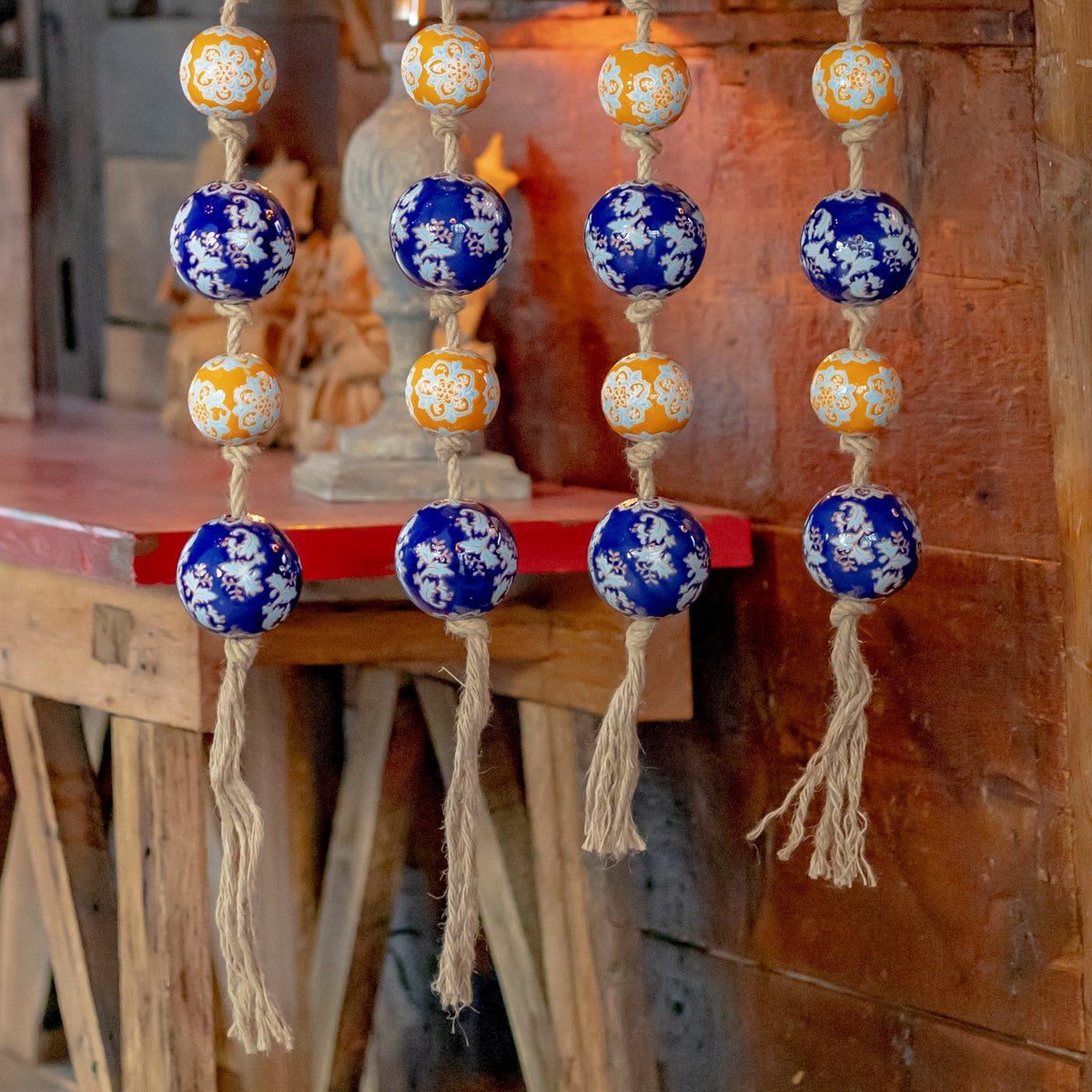 The lower portions of four ball strands show blue and orange ornaments and loose twine tassels.