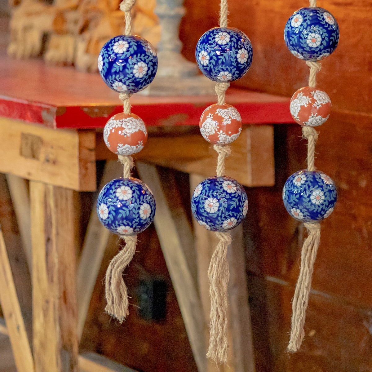 Three close strands show glossy floral-patterned balls and frayed cord ends.