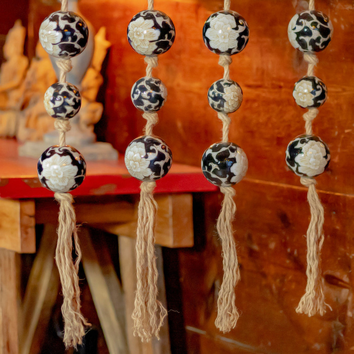 Rope tassels hang below black-and-white patterned balls in front of a rustic interior.