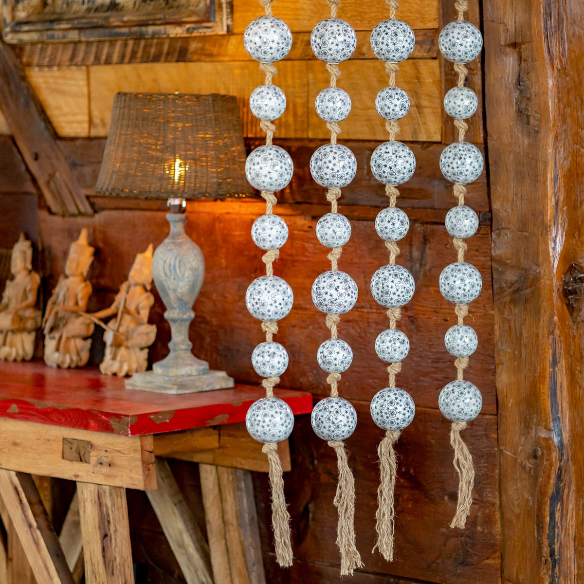 The lower ends of four ball garland strands show knotted cords and loose jute tassels.