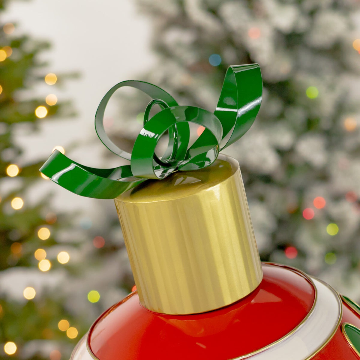 Close detail of the ornament’s curled green bow and cylindrical gold cap.