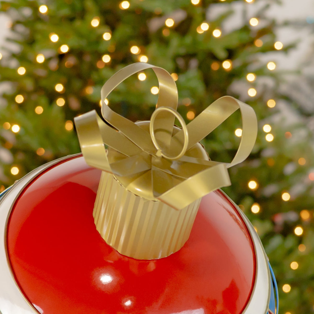 Close-up of the ornament’s gold cap and curled loops above its glossy red top.