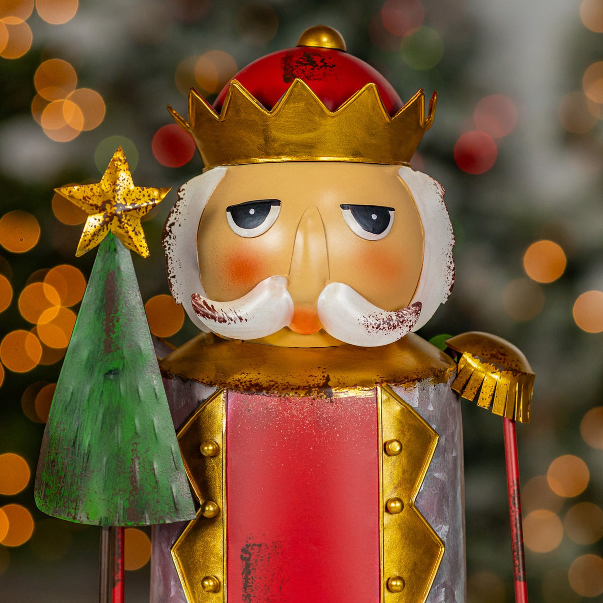 Close-up of the nutcracker's painted face, gold crown and green Christmas tree