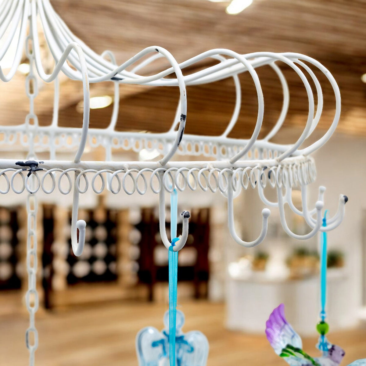 Close view of curved white metal hooks and looped trim on the display frame