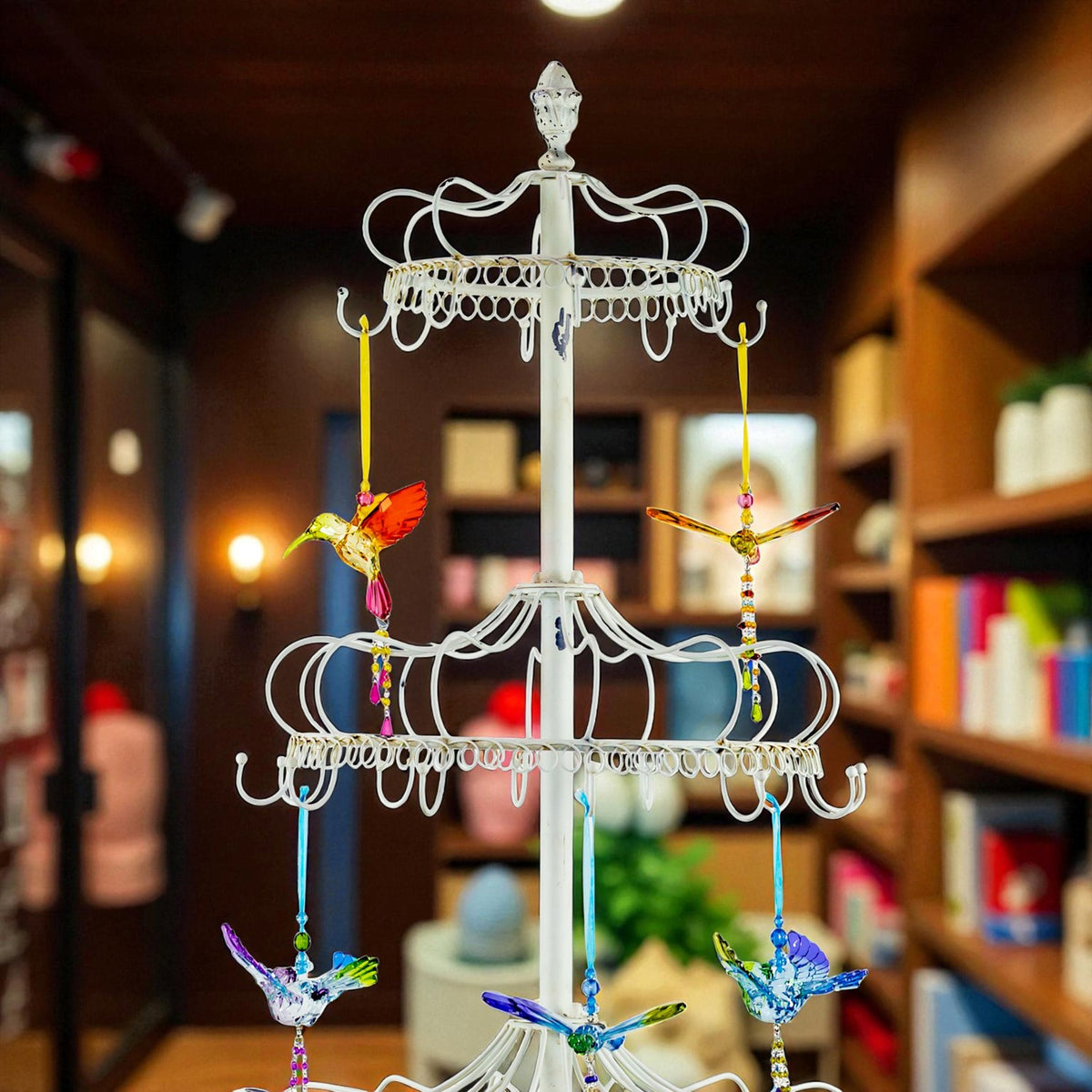 Upper portion of the ivory display stand showing its finial, top tier, and suspended bird ornaments.