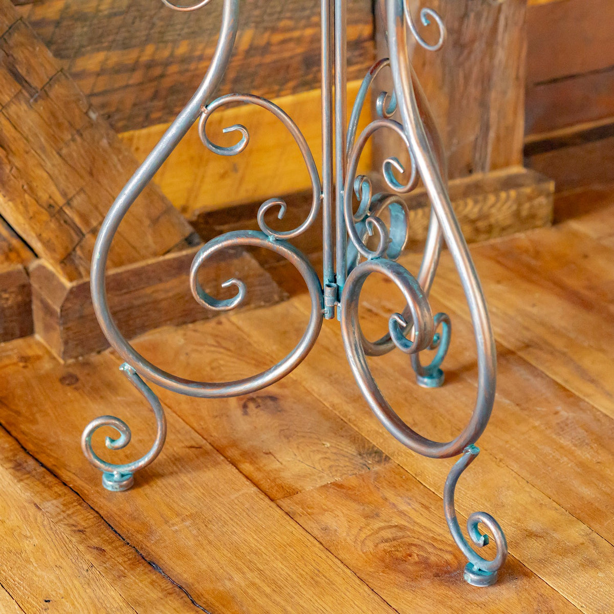 Curving metal legs and scrollwork meet the wooden floor at the stand's base.