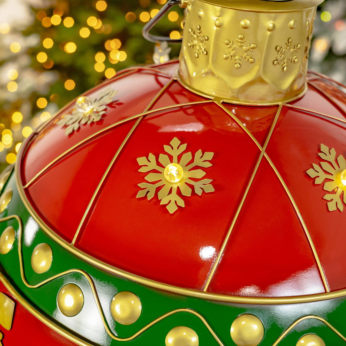 Angled close-up of a glowing gold snowflake, red panels, and a green-and-gold decorative band.