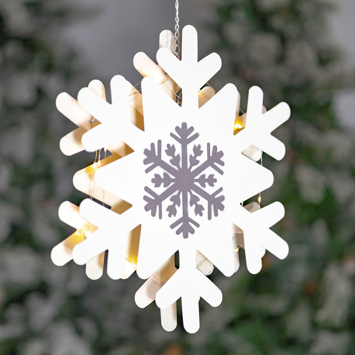 Detailed view of a white snowflake decoration with a silver center and glowing lights