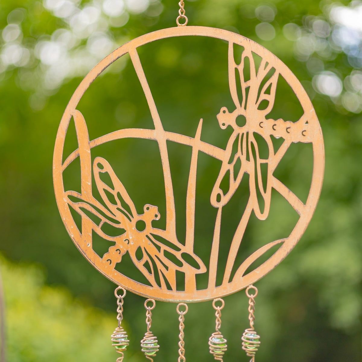 Copper-finish circular wind chime with dragonflies in a close outdoor view