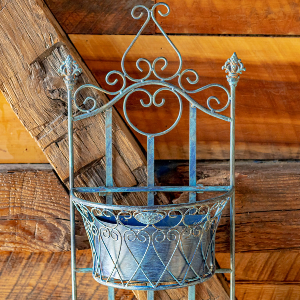 Close-up of the planter's curled blue metal crest and the wirework around its basket.