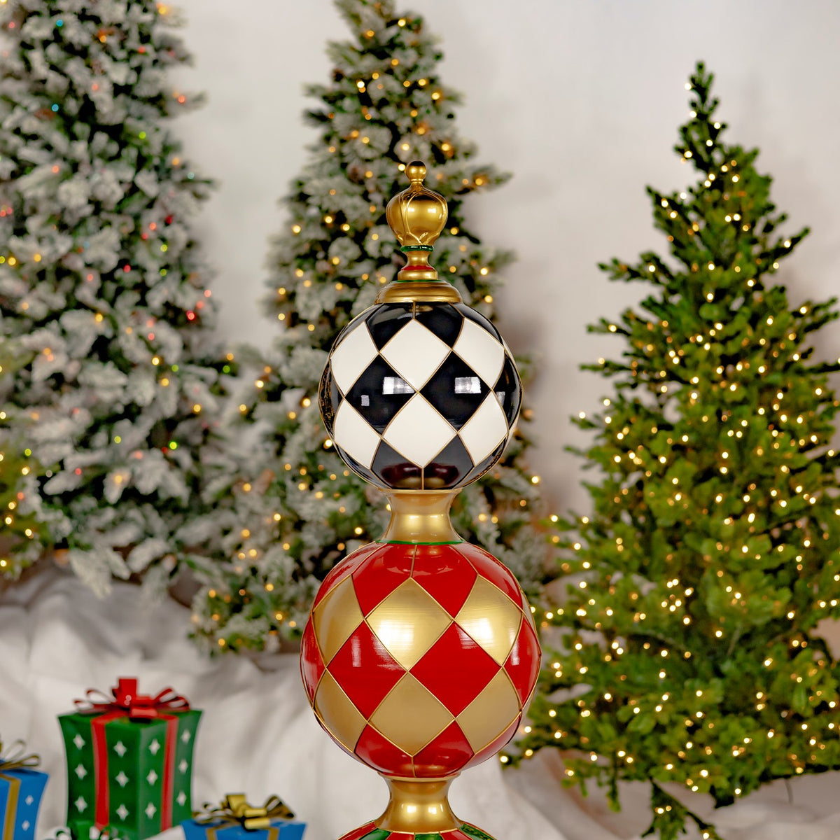 The tower’s black-and-cream diamond sphere and red-and-gold patterned sphere are shown against lit trees.