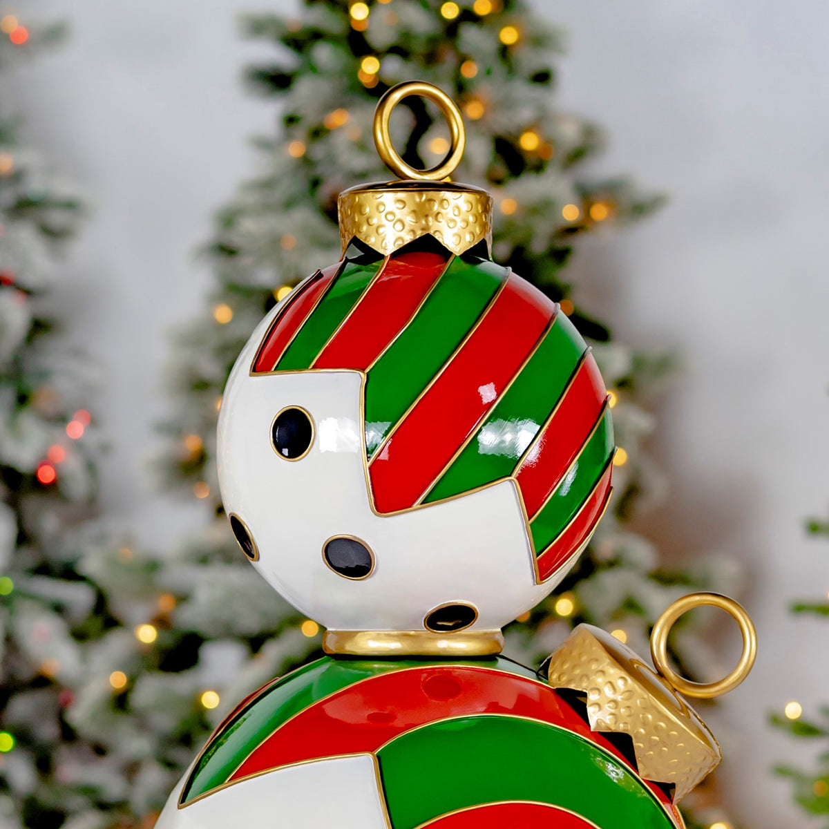 Close-up of glossy red-and-green stripes, black dots, gold edging, and looped caps on the stacked ornaments.