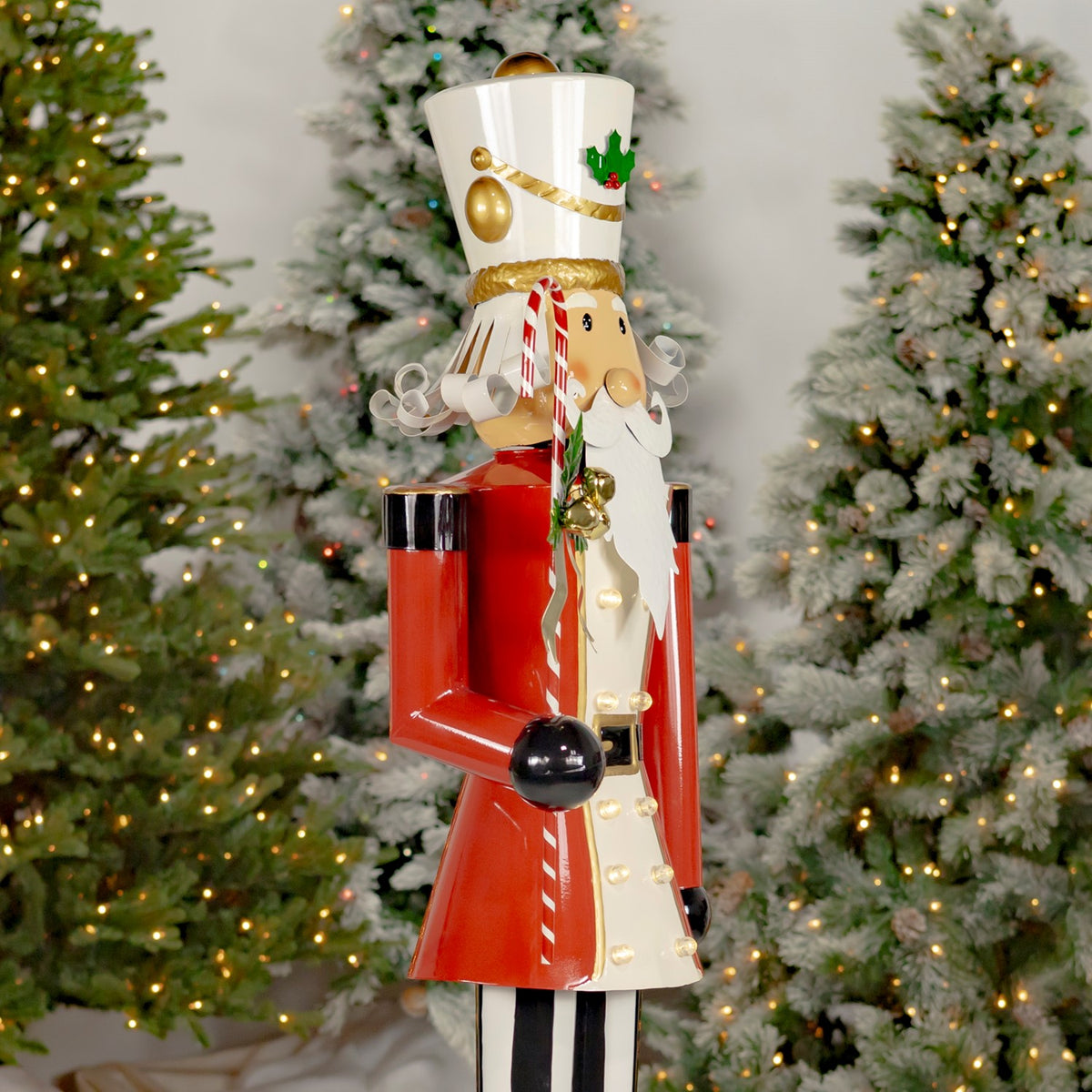 Side view of the nutcracker showing its red coat, striped candy cane, and black hands.
