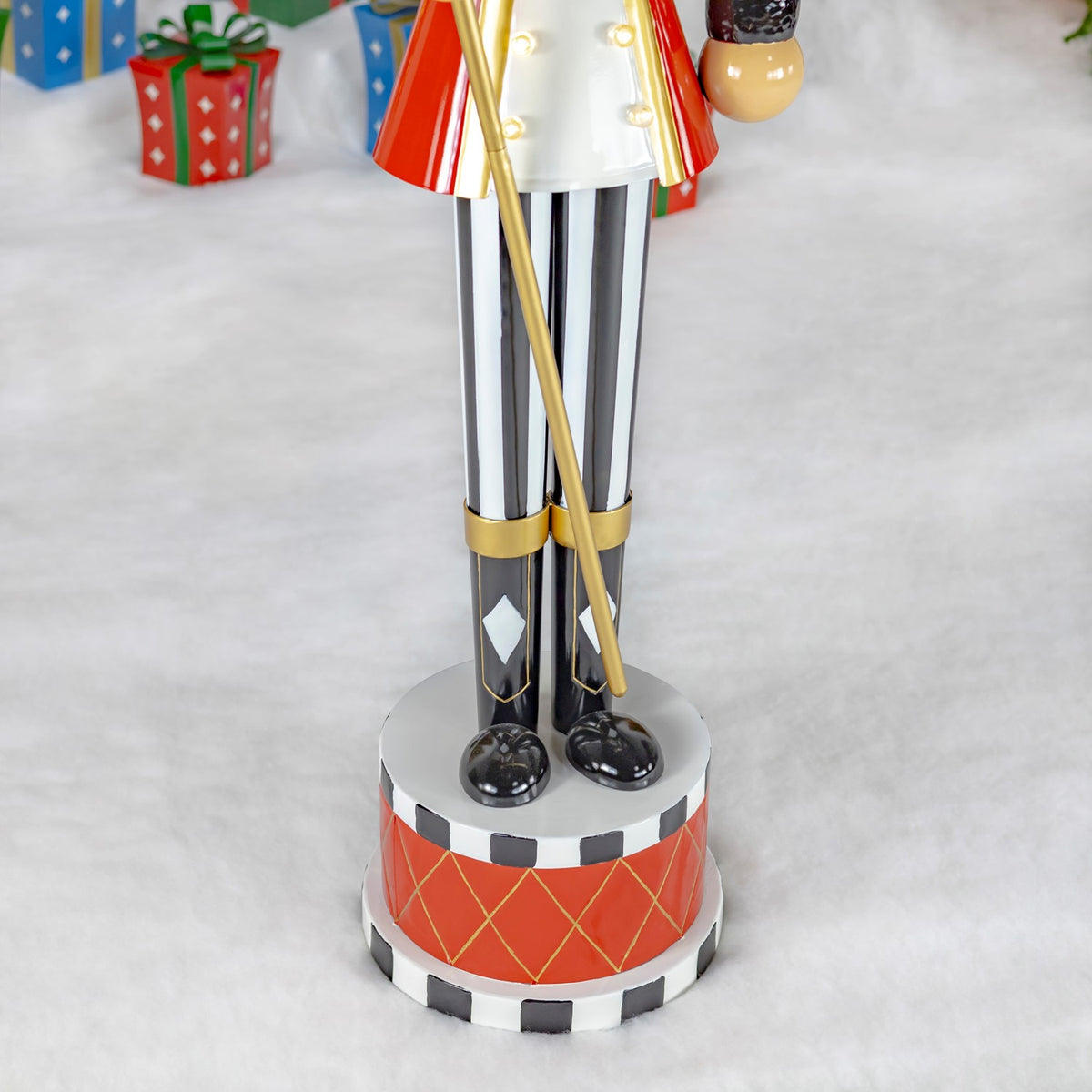 Close-up of the nutcracker’s striped trousers, black boots, gold staff and red patterned base.