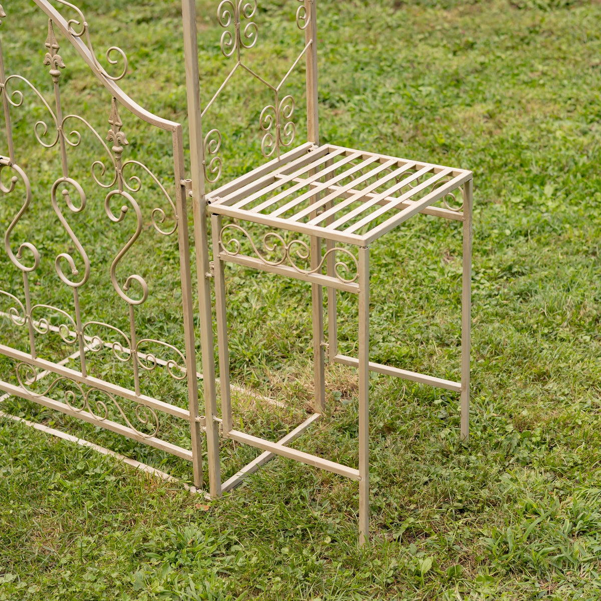 Rectangular slatted plant stand attached beside the iron garden gate