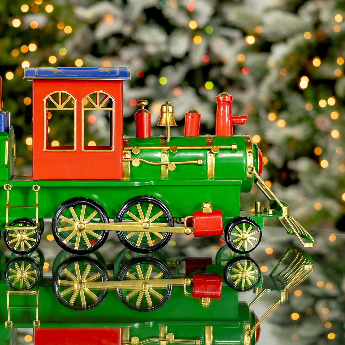 Close side view of the red cab and green locomotive against a lit tree