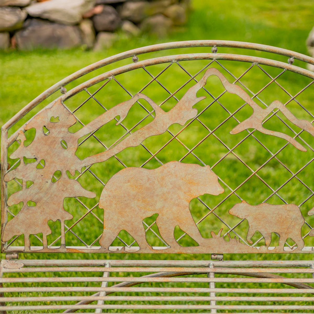 Close-up of textured metal bear and cub silhouettes with mountain shapes on the bench back.