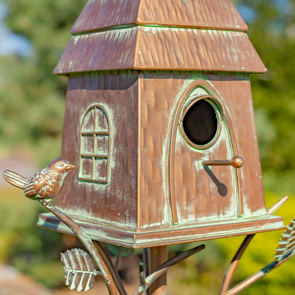 Front close-up of the birdhouse entry hole, perch, and distressed copper finish