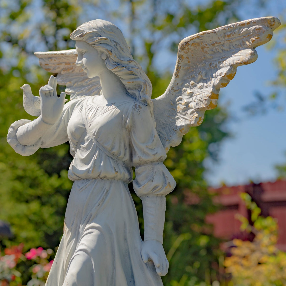 Angled view of the angel statue with outstretched wings, a flowing dress, and one hand raised.