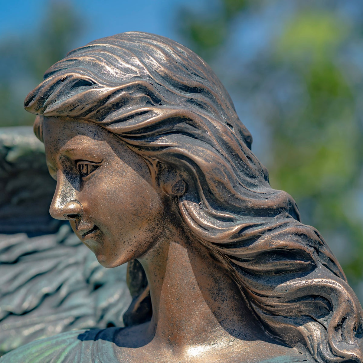 Close-up of the angel’s profile, showing wavy hair and a weathered bronze-toned finish.