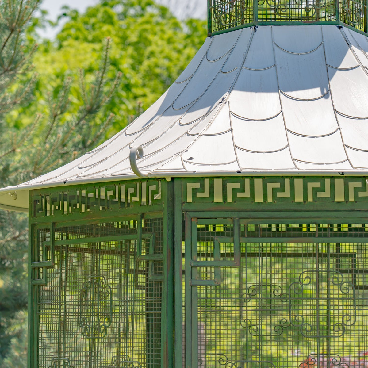 Close view of a pale pagoda-style roof above green lattice panels with geometric trim.