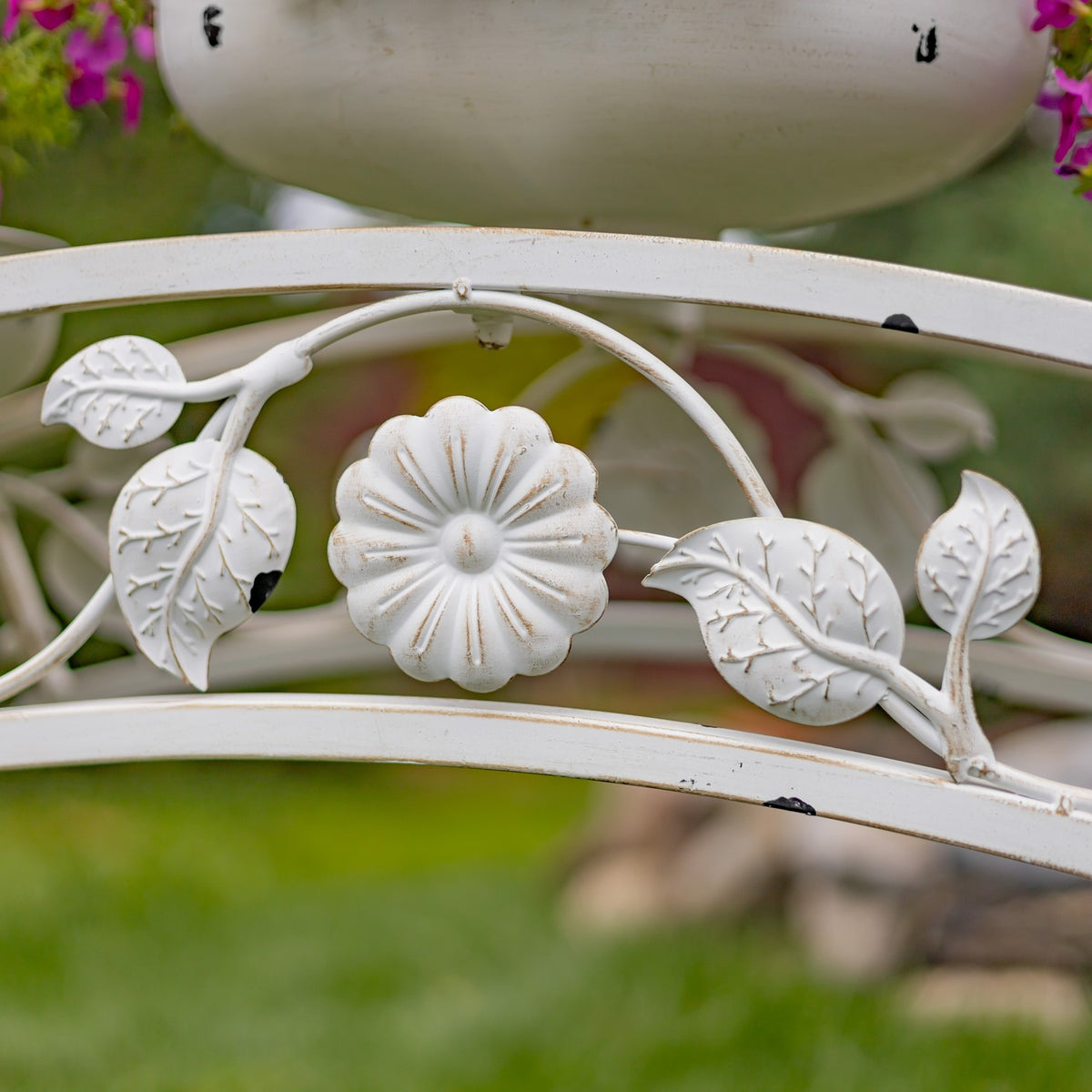 Close-up of a sculpted flower and leaf motifs on the stand’s white metal frame.
