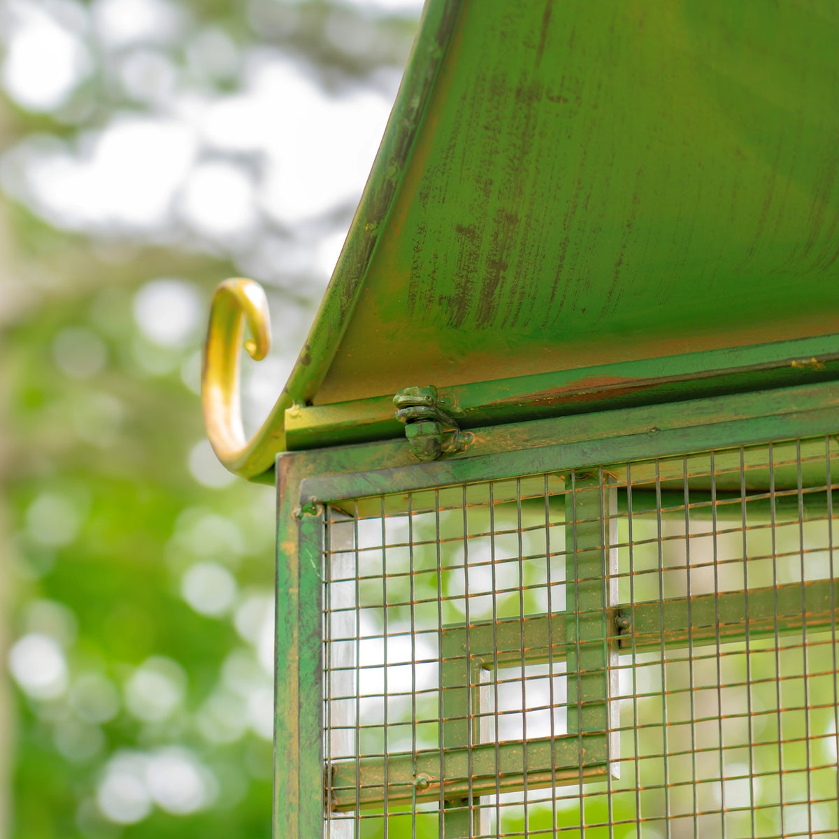 Close-up beneath the green roof showing a metal hinge, mesh panel and weathered finish.