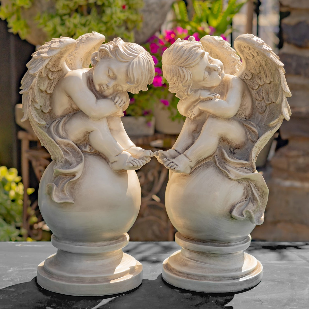 Two distressed cherub statues facing each other on outdoor pedestals