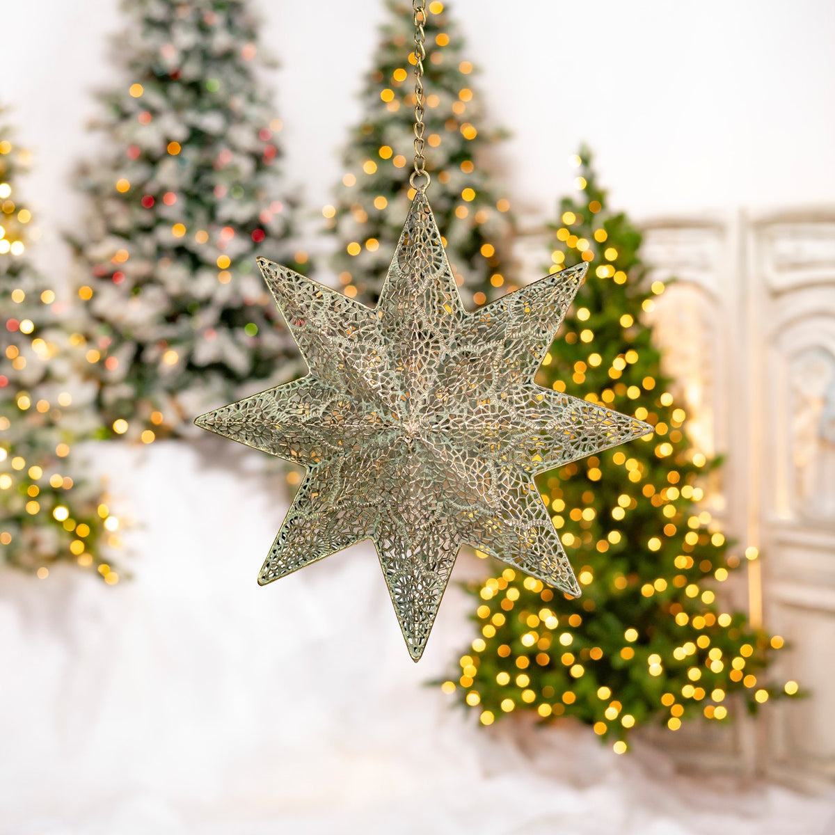 A hanging gold star ornament is seen from another angle against glowing Christmas trees.