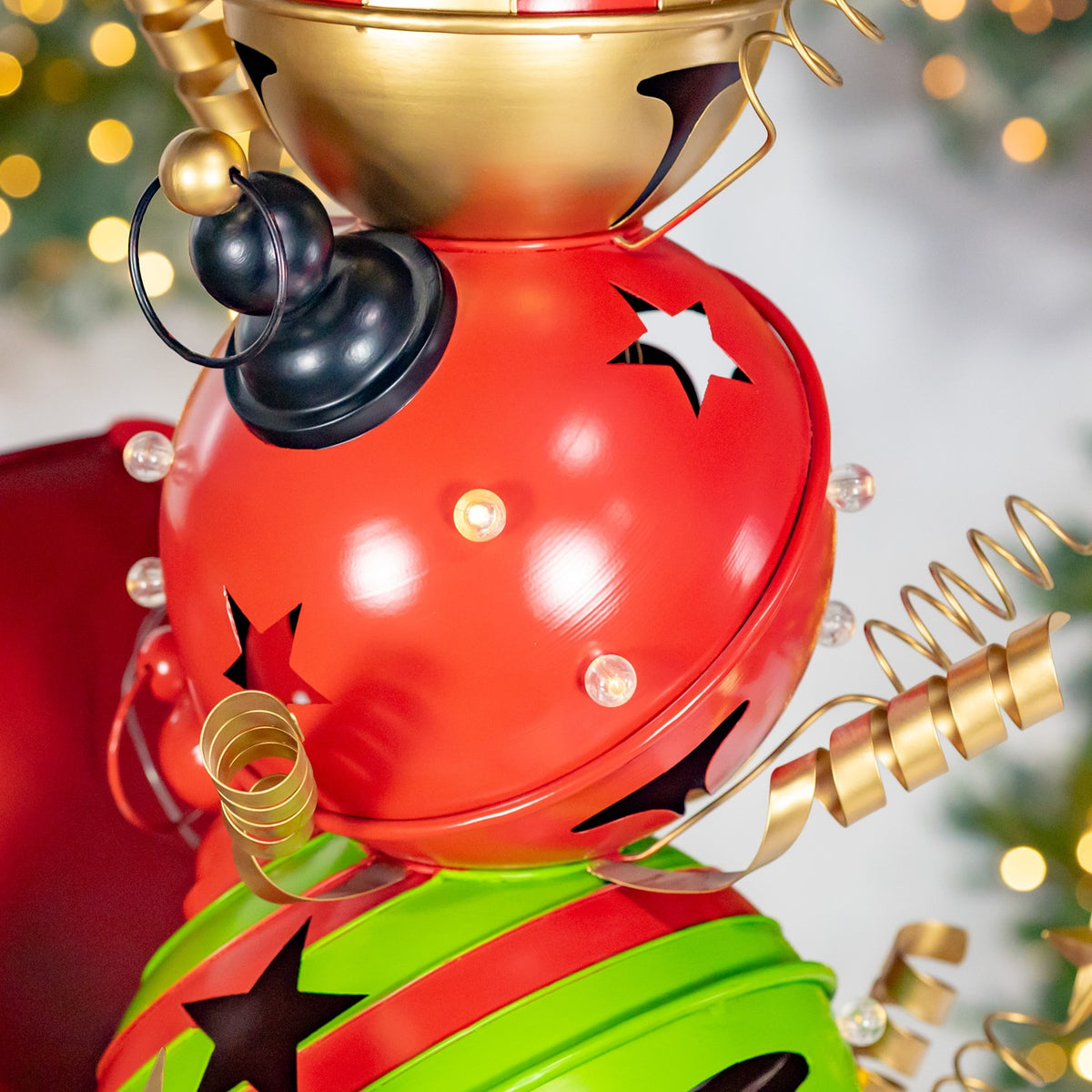 A red rounded figure with star cutouts, black bells and gold spiral accents above a green figure.