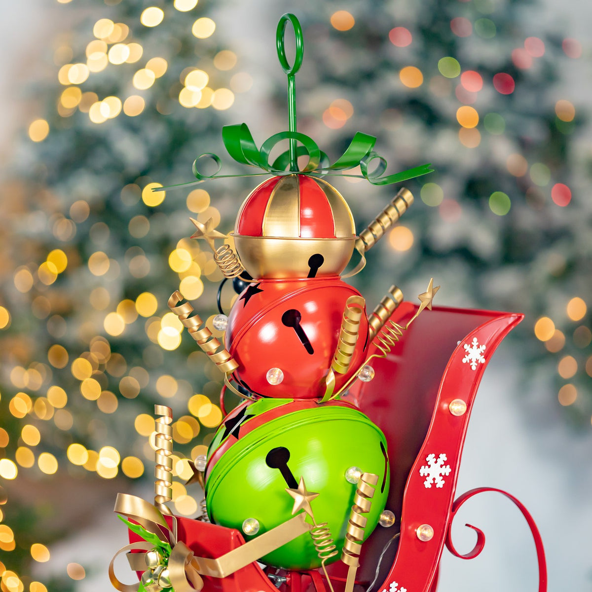 Upper portion of the sleigh display, showing the snowman’s rounded sections, gold accents and green bow.