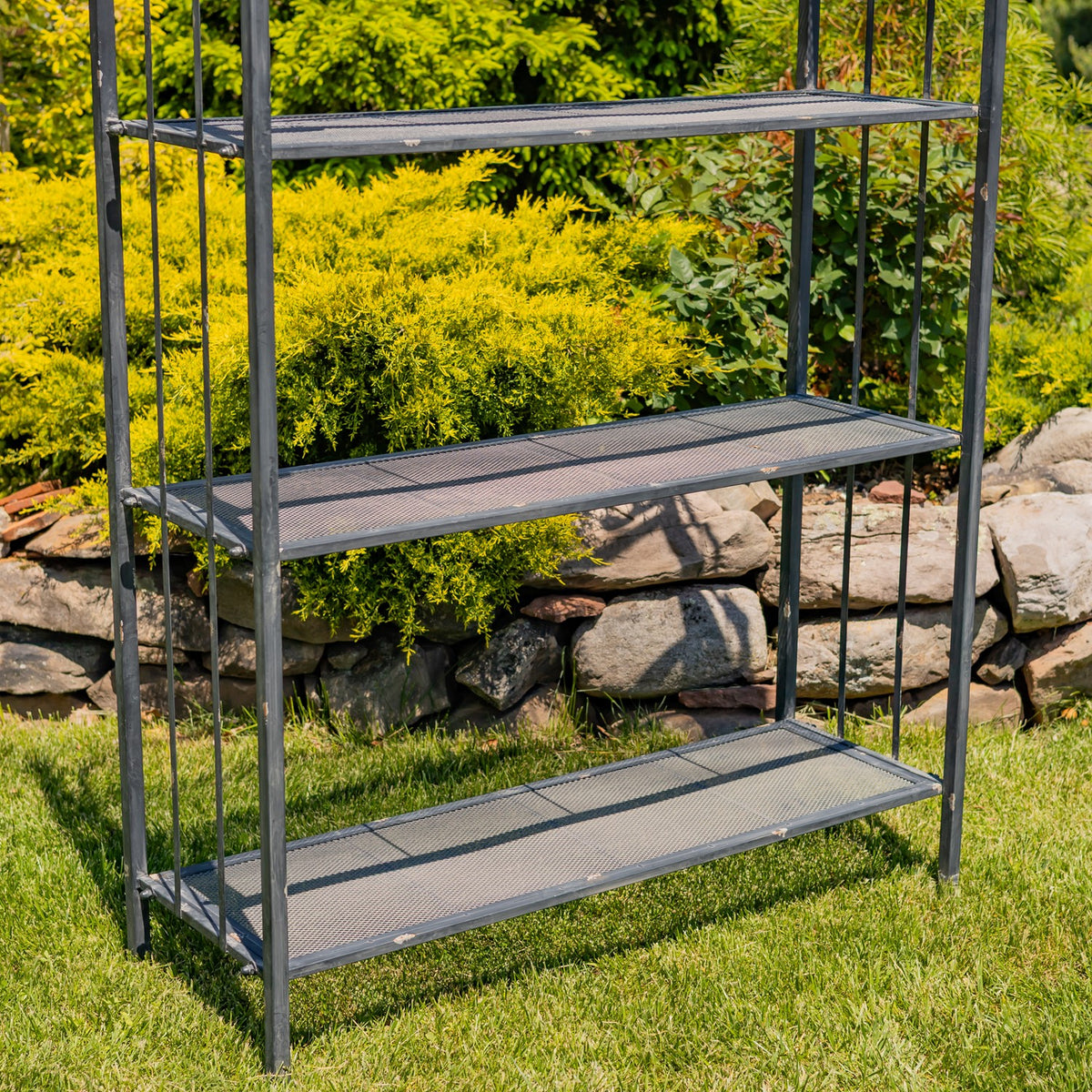Close view of three lower mesh shelves and the slim iron support posts.