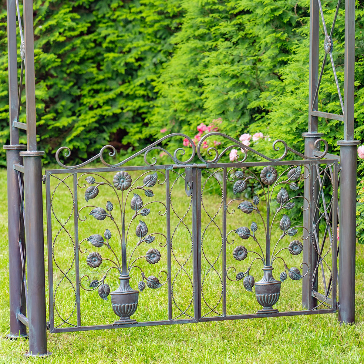 Close view of a metal gate panel decorated with leafy vines, flowers and two urn-shaped accents.