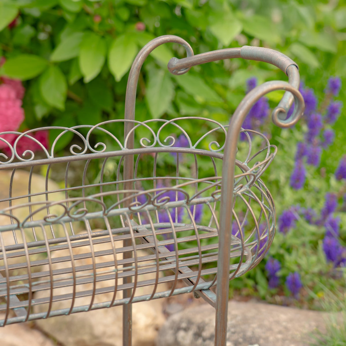 Close-up of a curled handle, curved wire rim, and woven metal sides of the basket.